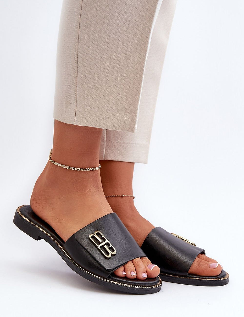Woman wearing Tavirelle Gold Trim Leather Slides, showcasing sleek design with gleaming gold accent, perfect for warm-season outfits.
