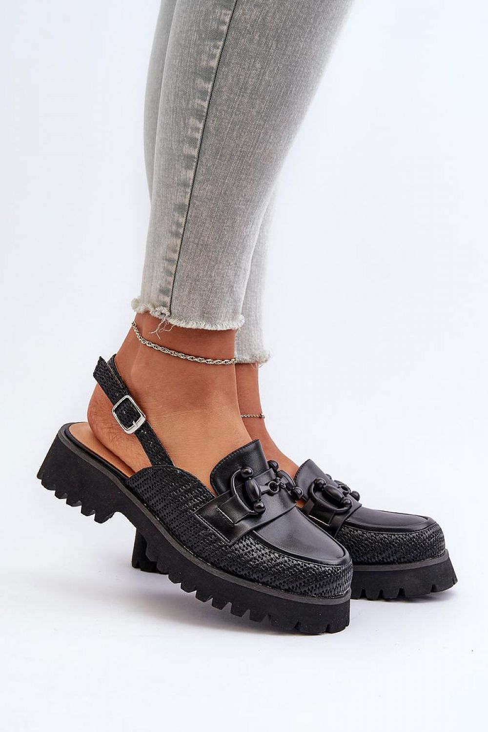 Larivena Buckled Low Platform Sandals in black eco leather with adjustable buckle, worn on feet with gray jeans, showcasing stylish comfort.