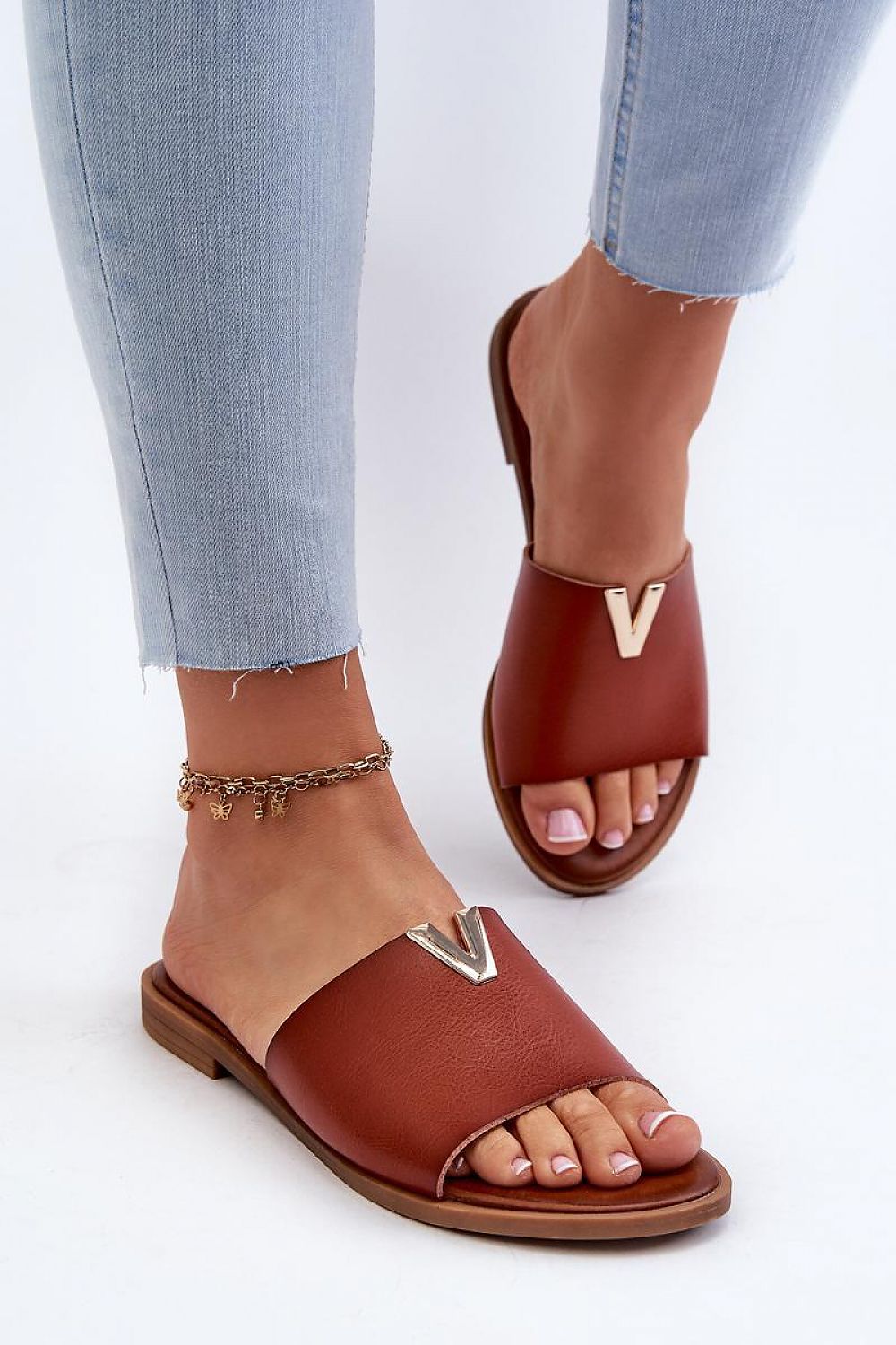 Talvera flat slides with gold accent, made from smooth eco leather, shown worn with light jeans, highlighting their minimalist design.