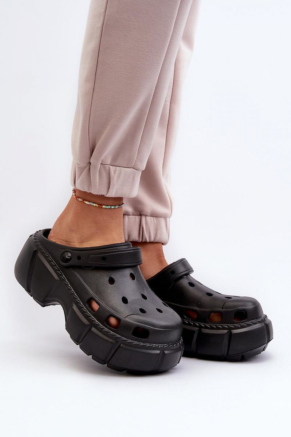 Black sculpted foam beach slides worn with light pants, featuring a thick sole for support and minimalist design ideal for summer.