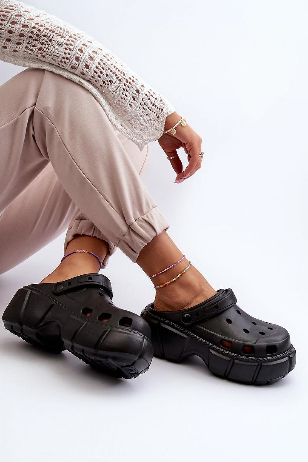 Modern sculpted foam beach slides in black, featuring a thick sole and minimalist design, worn with beige pants and a white top.