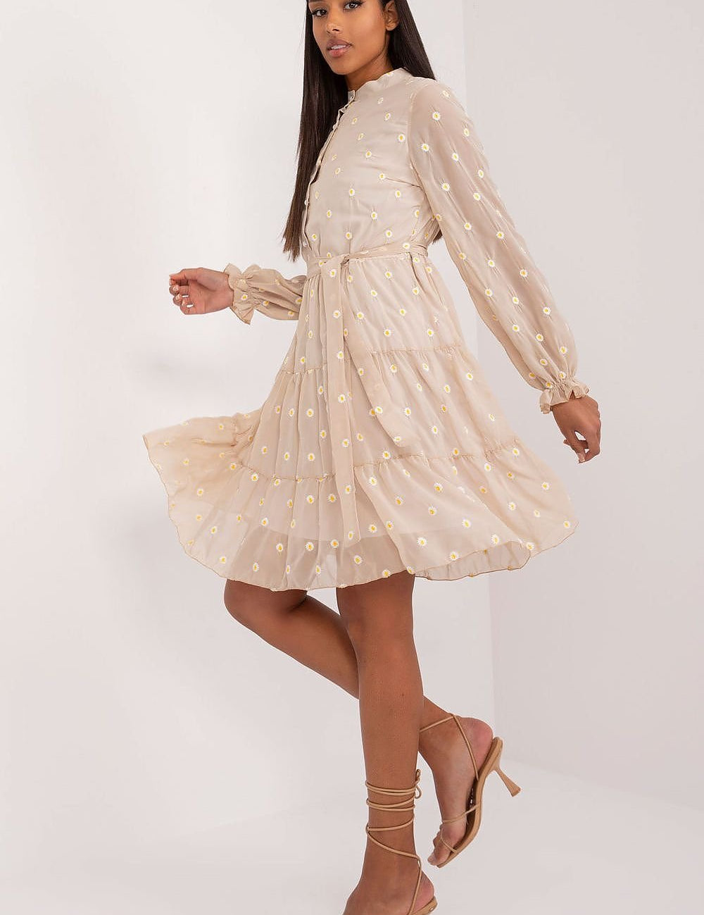Woman in a beige floral dress with long puffed sleeves and a flared skirt, exuding vintage elegance and sophistication.