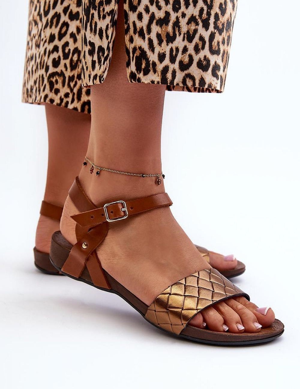 Woman wearing Sorellia Buckled Leather Sandals with adjustable buckle strap, paired with a leopard print skirt, for summer city walks.