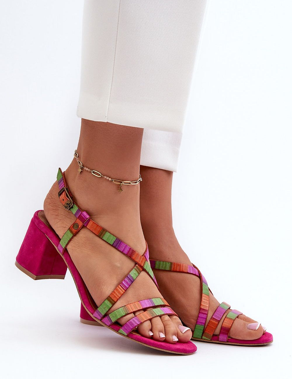 Colorful strappy leather sandals with mid-heel and ankle bracelet, styled with white trousers for summer elegance.