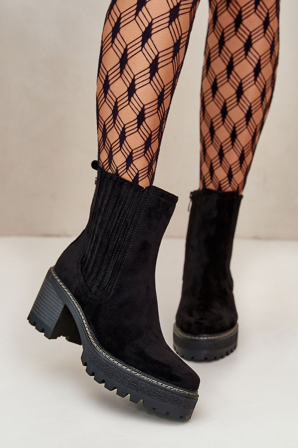 Aurevyn Hollowrise Cold Poise black ankle boots with block heel and rounded toe, paired with patterned tights. Perfect for refined style.