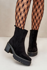 Aurevyn Hollowrise Cold Poise black ankle boots with block heel and rounded toe, paired with patterned tights. Perfect for refined style.