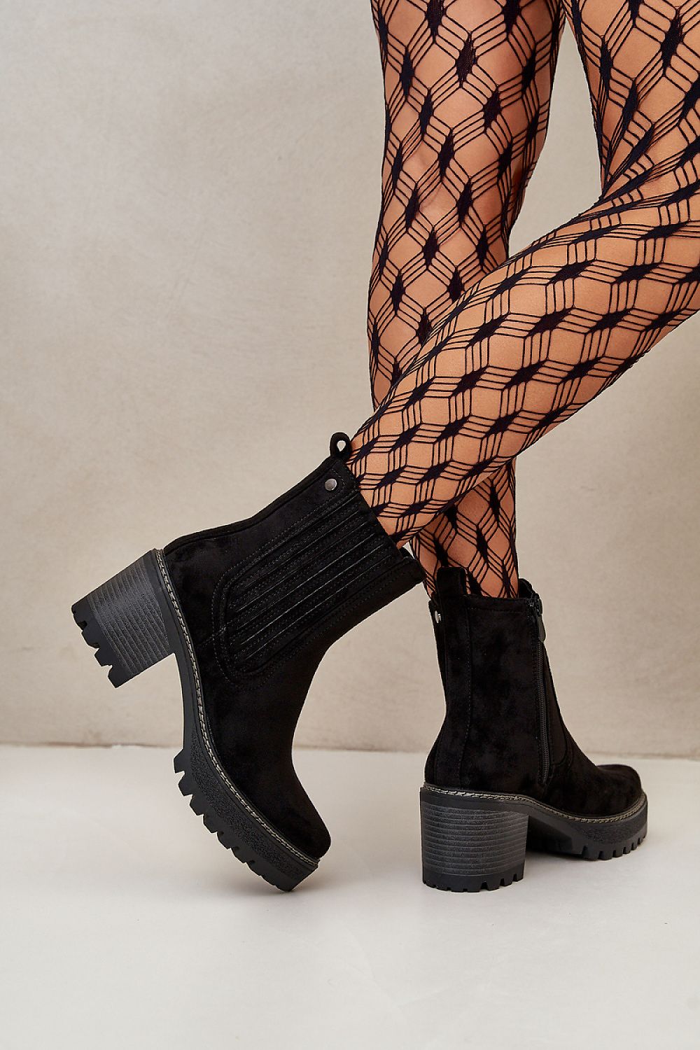 Aurevyn Hollowrise Cold Poise suede-finish ankle boots with stable block heel, rounded toe, and discreet zipper, worn with patterned tights.