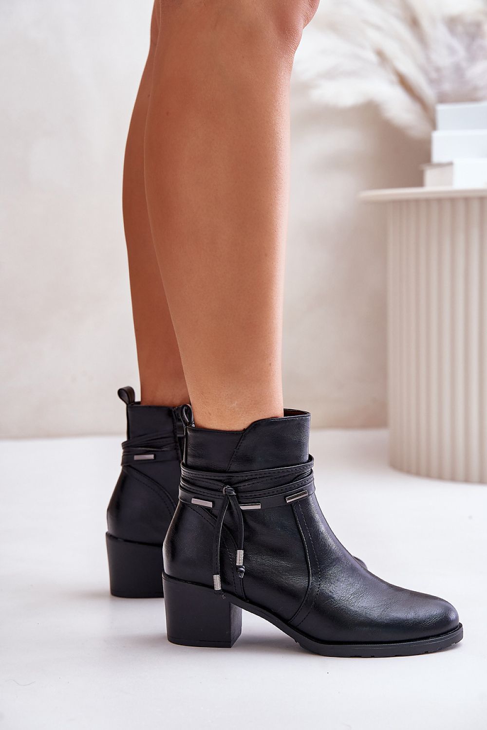 Woman wearing Olivaya eco-leather mid-heel black boots with decorative stripe, showcasing rounded toe and post-style heel.