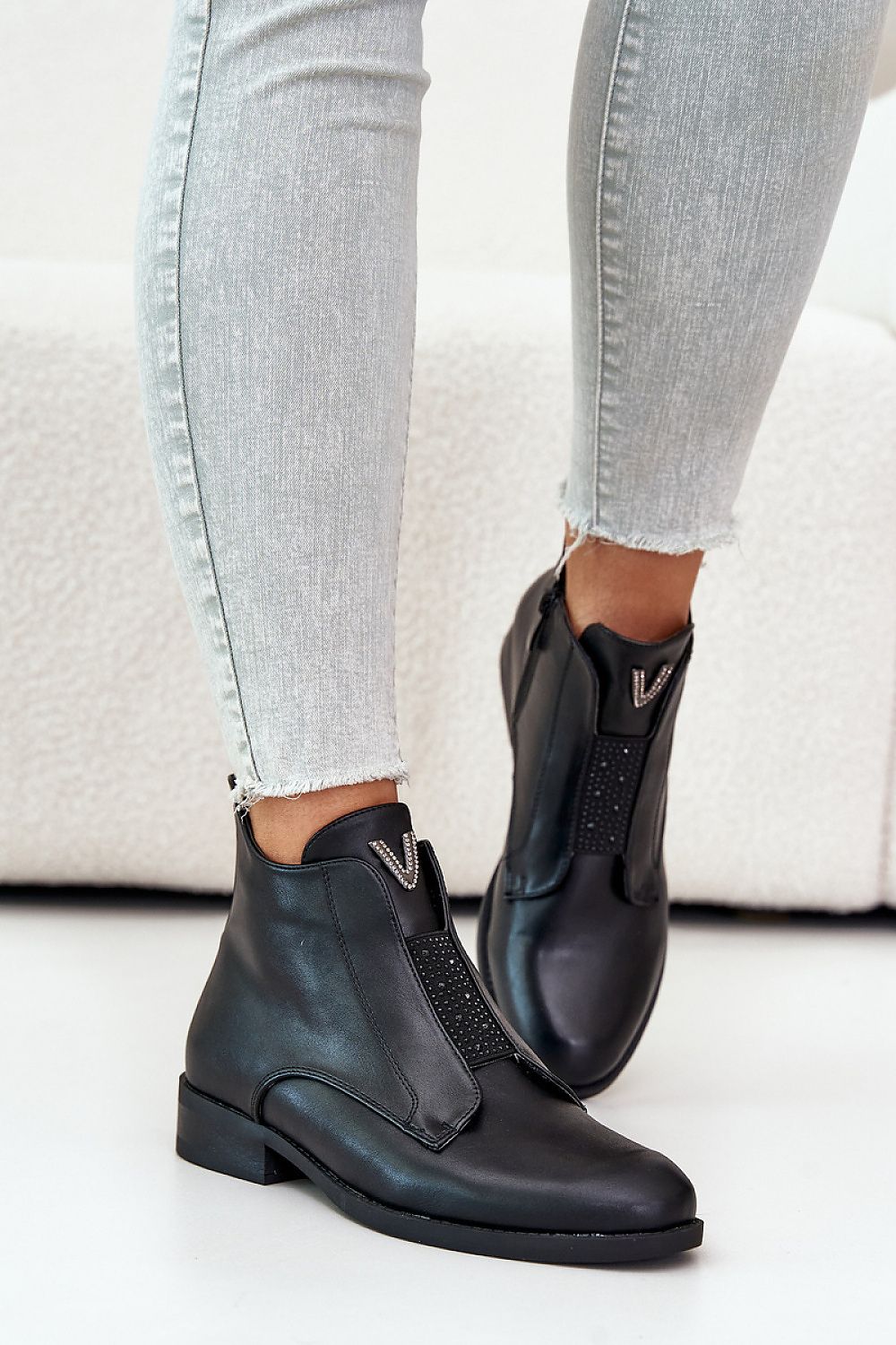 Person wearing Melvaren Zip-Up Ankle Winter Boots in black eco leather with side zipper and decorative tongue element.
