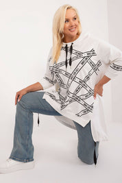 Plus size model in Elverra rhinestone blouse with asymmetrical cut and 3/4 sleeves, paired with jeans, showcasing casual elegance.