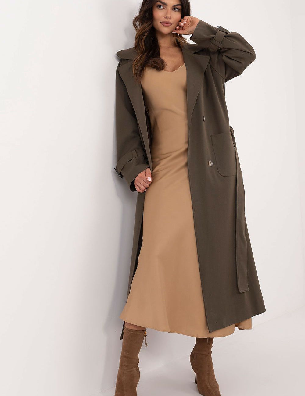 Model wearing Auremere double-breasted trench coat over camel dress, showcasing elegant, versatile women's fashion for all seasons.