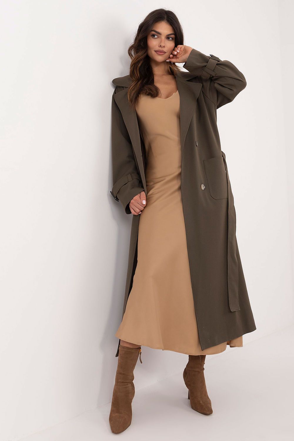 Model wearing Auremere double-breasted trench coat over camel dress, showcasing elegant, versatile women's fashion for all seasons.