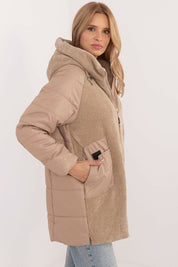 Woman wearing Cordivelle Quilted Hooded Jacket with corduroy panel and smooth quilted sections, featuring durable polyester and zip closure.