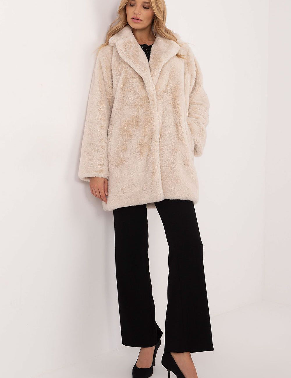 Woman wearing a sophisticated knee-length beige coat, styled for autumn-winter transition, combining comfort and elegance.