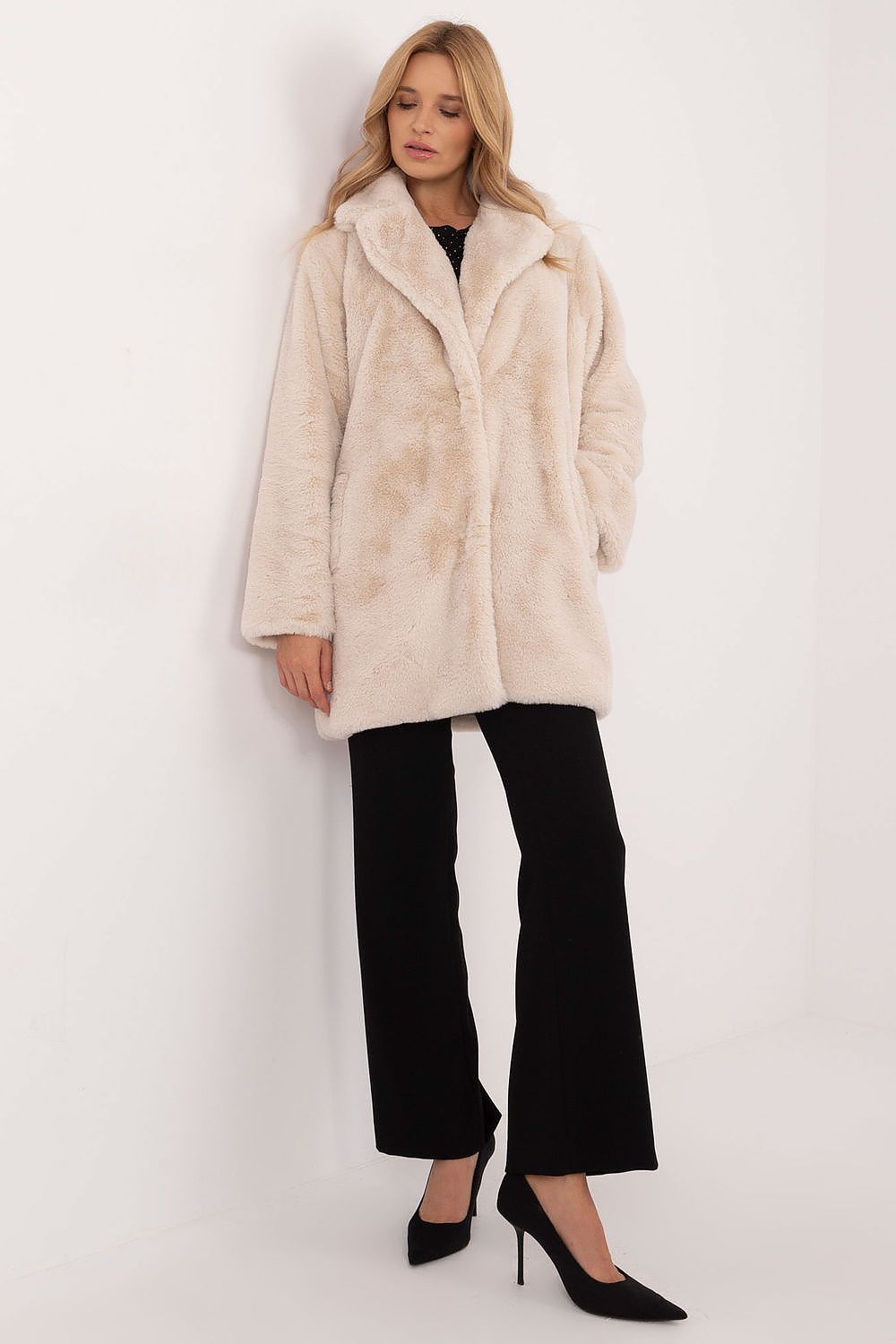 Woman wearing a sophisticated knee-length beige coat, styled for autumn-winter transition, combining comfort and elegance.