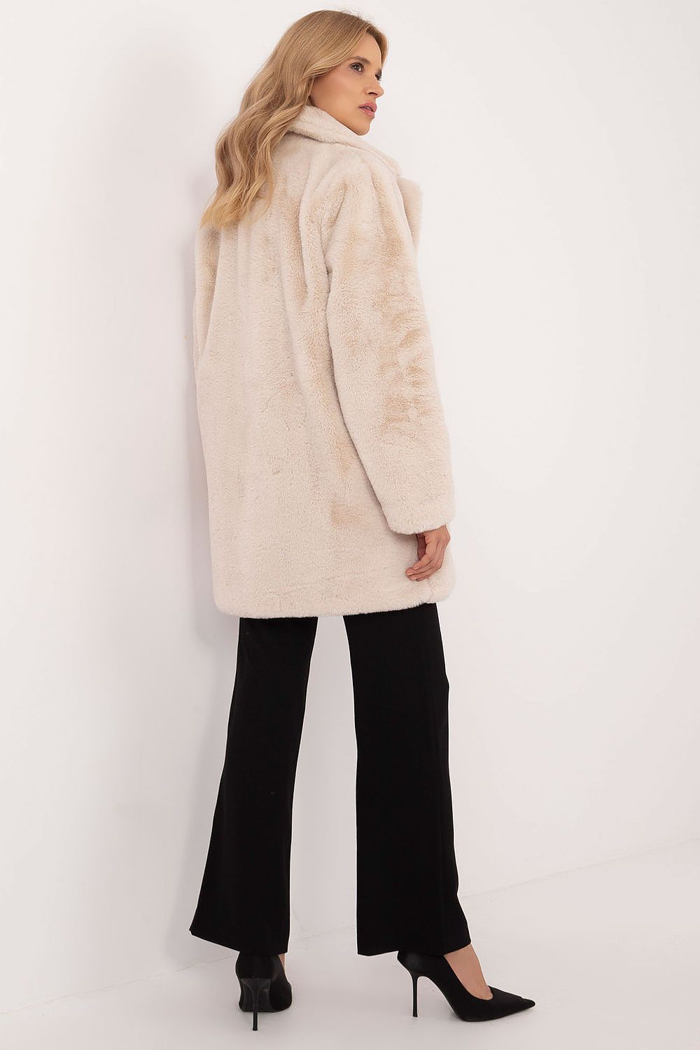 Woman wearing a beige viscose mid-season coat with knee-length coverage and black trousers, showcasing autumn-winter fashion.