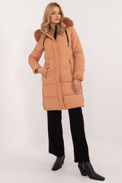 Woman wearing Arden Quilted Longline Winter Jacket with detachable hood and fur trim, showcasing warmth and elegance.