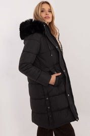 Woman wearing Arden Quilted Longline Winter Jacket with detachable hood and fur trim, knee-length, perfect for autumn and winter.