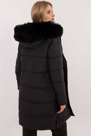 Woman wearing Arden Quilted Longline Winter Jacket with black fur-trimmed hood, showcasing back view and sleek design.