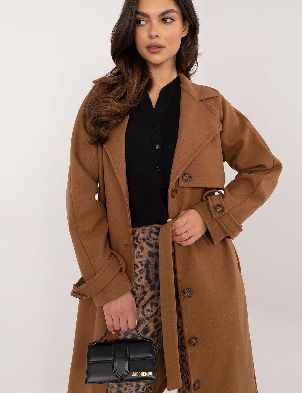Woman wearing Meriselle Belted Weather-Resistant Trench in brown, featuring button closure and waist belt, paired with leopard print pants.