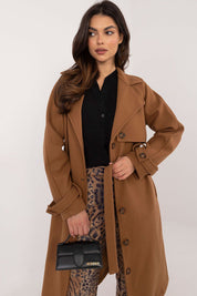 Woman wearing Meriselle Belted Weather-Resistant Trench in brown, featuring button closure and waist belt, paired with leopard print pants.