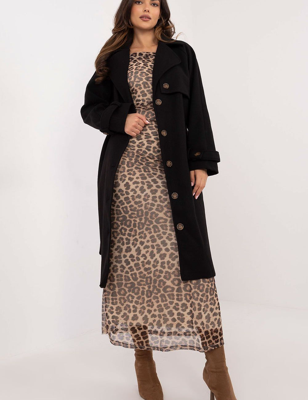 Woman in leopard print dress wearing a black trench coat with button closure, showcasing a stylish and weather-resistant fashion choice.