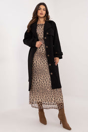 Woman in leopard print dress wearing a black trench coat with button closure, showcasing a stylish and weather-resistant fashion choice.