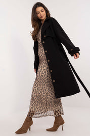 Woman modeling black Meriselle Belted Weather-Resistant Trench Coat over animal print dress with long sleeves and button closure.