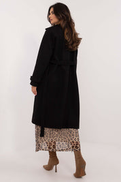 Back view of a woman wearing Meriselle Belted Weather-Resistant Trench in black, styled with leopard print skirt and tan boots.