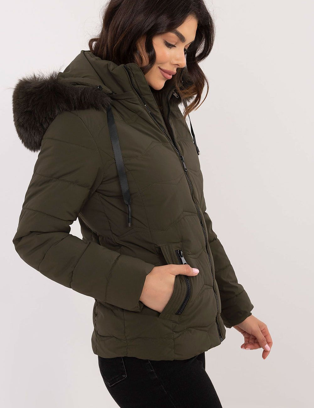Woman wearing Veyra Short Quilted Jacket with detachable hood, featuring sleek silhouette and quilted design in olive green.