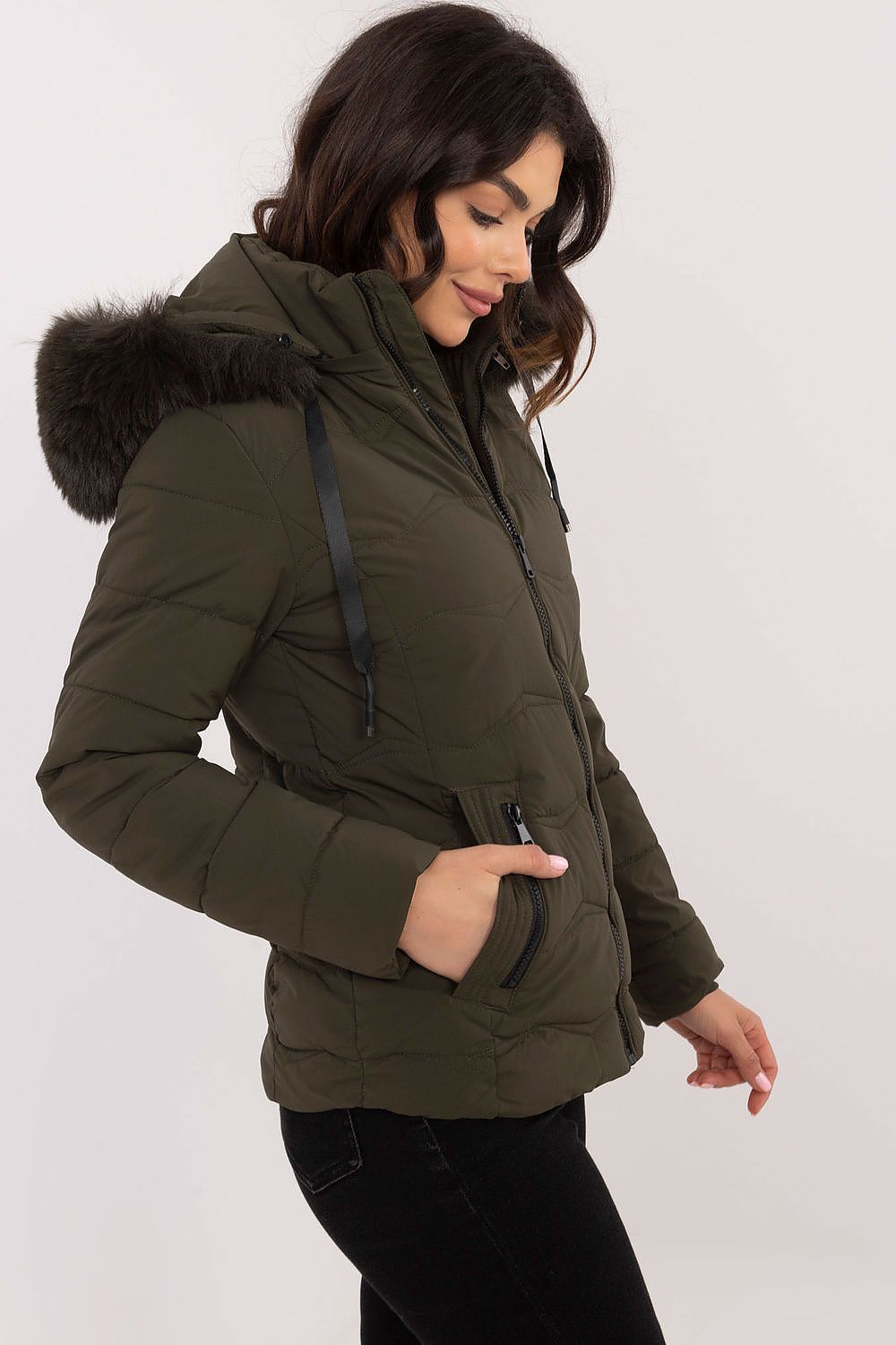 Woman wearing Veyra Short Quilted Jacket with detachable hood, featuring sleek silhouette and quilted design in olive green.