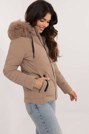 Woman wearing Veyra Short Quilted Jacket, featuring light brown quilted design, detachable fur hood, and front zipper for winter warmth.