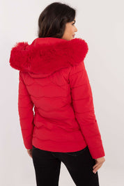 Woman wearing a red Veyra Short Quilted Jacket with a detachable hood, showcasing its sleek design and quilted pattern from the back view.