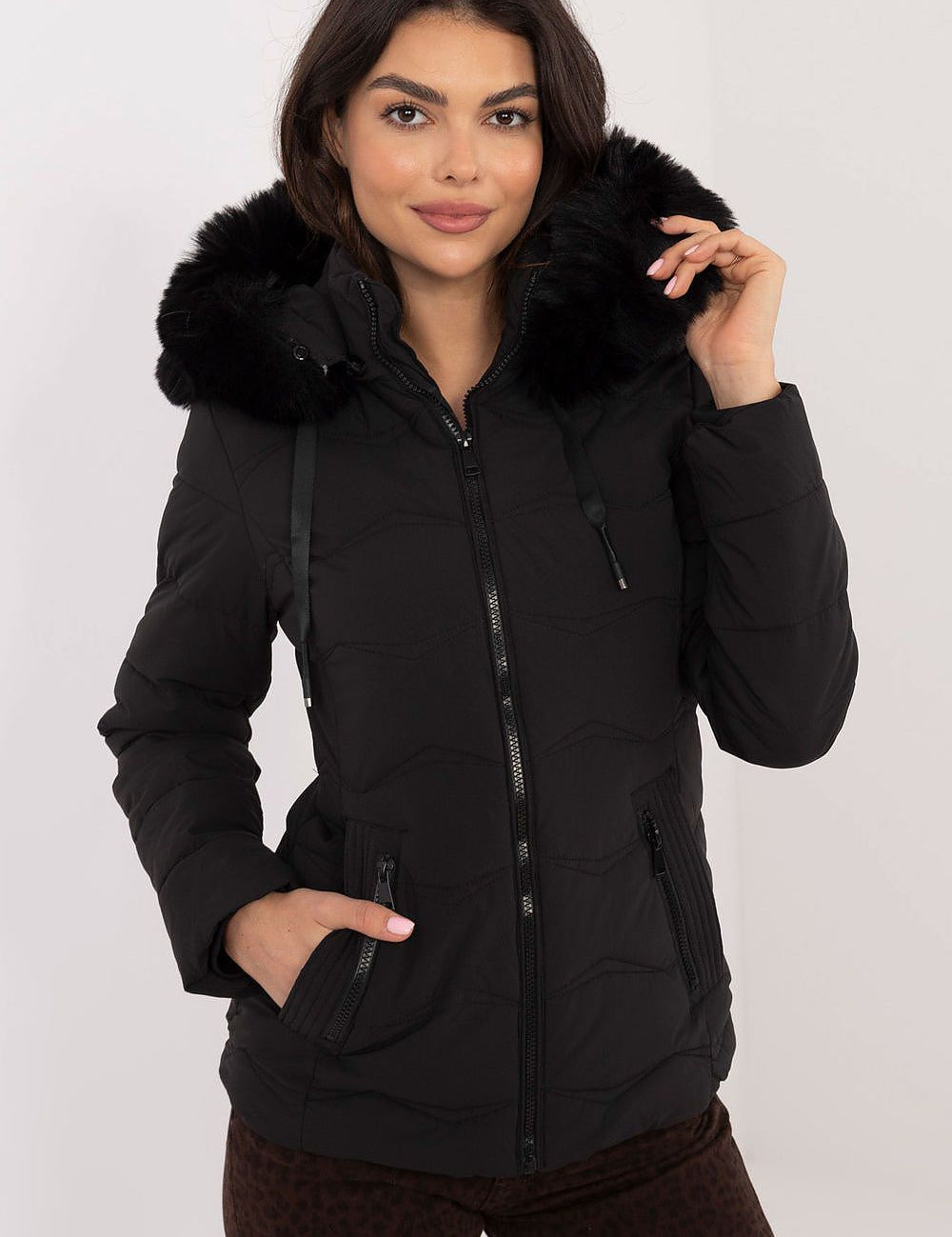 Woman wearing Veyra Short Quilted Jacket with detachable hood and full front zipper, featuring a sleek design and synthetic down filling for warmth.