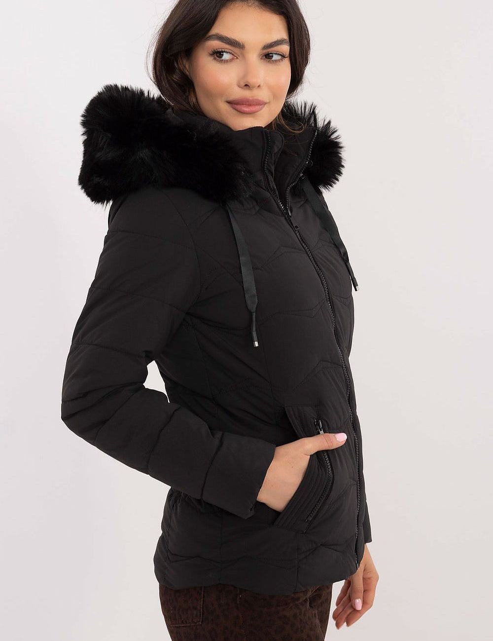 Woman wearing Veyra Short Quilted Jacket with detachable hood, showcasing sleek silhouette and quilted design for cold weather.