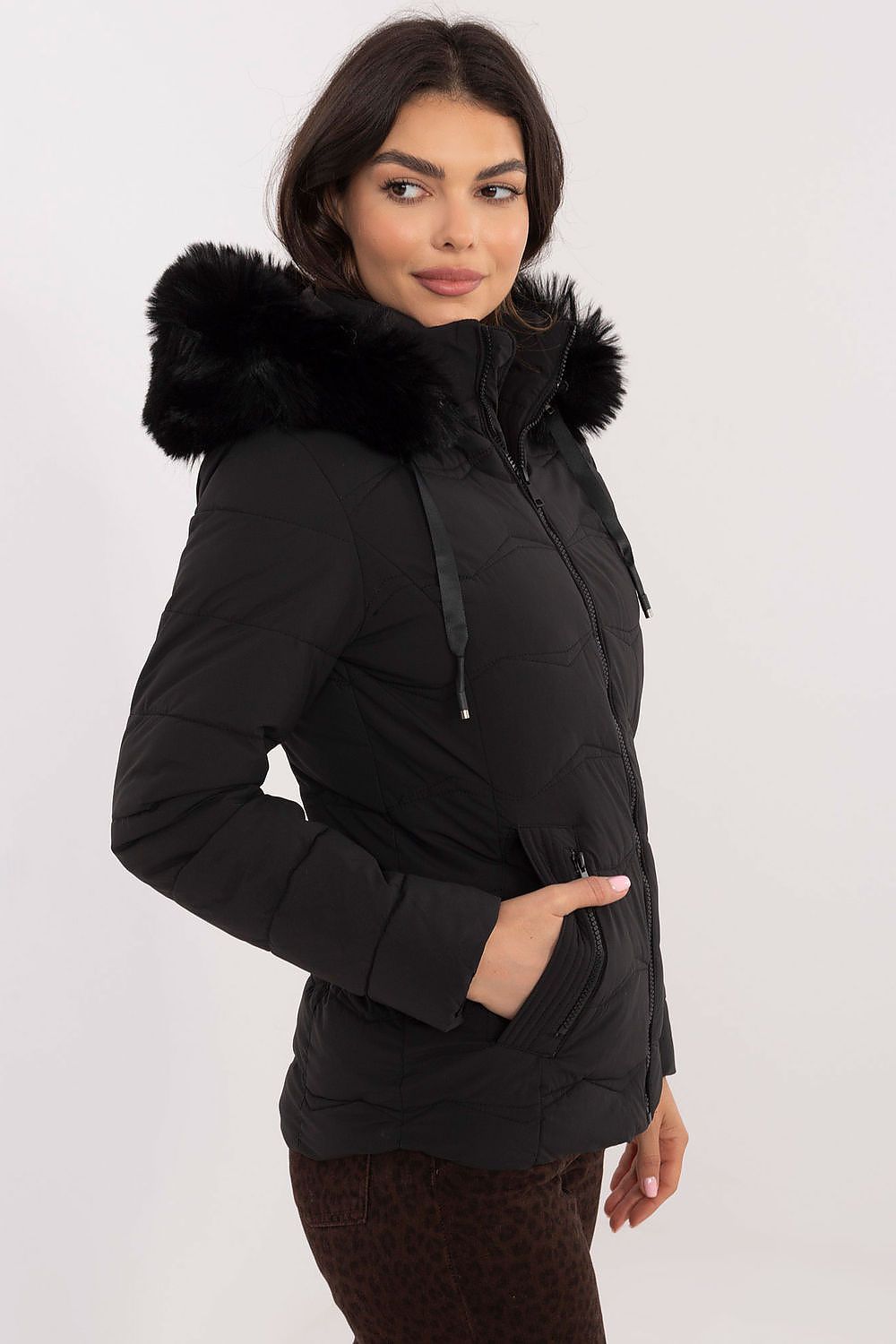 Woman wearing Veyra Short Quilted Jacket with detachable hood, showcasing sleek silhouette and quilted design for cold weather.