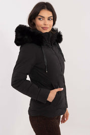 Woman wearing Veyra Short Quilted Jacket with detachable hood, showcasing sleek silhouette and quilted design for cold weather.