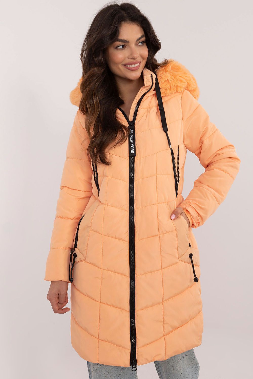 Woman wearing Aurlis Quilted Winter Jacket, peach, with detachable faux fur trim, knee-length coverage for warmth and style.