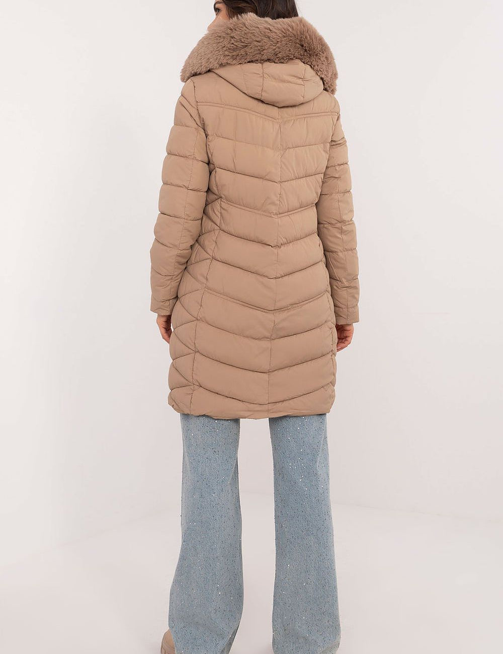 Back view of a woman wearing a beige Frostveil Quilted Winter Jacket with detachable faux fur trim, showcasing the quilted design.