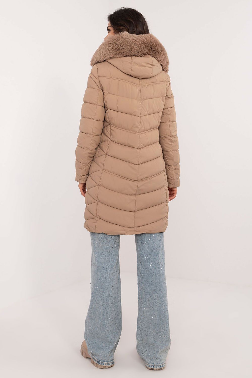 Back view of a woman wearing a beige Frostveil Quilted Winter Jacket with detachable faux fur trim, showcasing the quilted design.