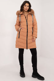Woman wearing Frostveil Quilted Winter Jacket with faux fur trim, showcasing knee-length style and warmth for cold weather.