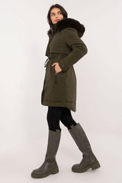 Woman wearing Frostveil Quilted Winter Jacket in olive green with detachable faux fur trim and hood, showcasing modern style and warmth.