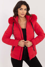 Woman wearing Veyra Short Quilted Jacket in red with detachable hood, showcasing sleek silhouette and contemporary quilted design.