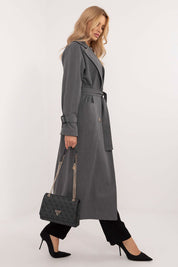 Elegant woman in Elandra double-breasted trench coat, calf-length, classic style, carrying a handbag, wearing black pants and heels.