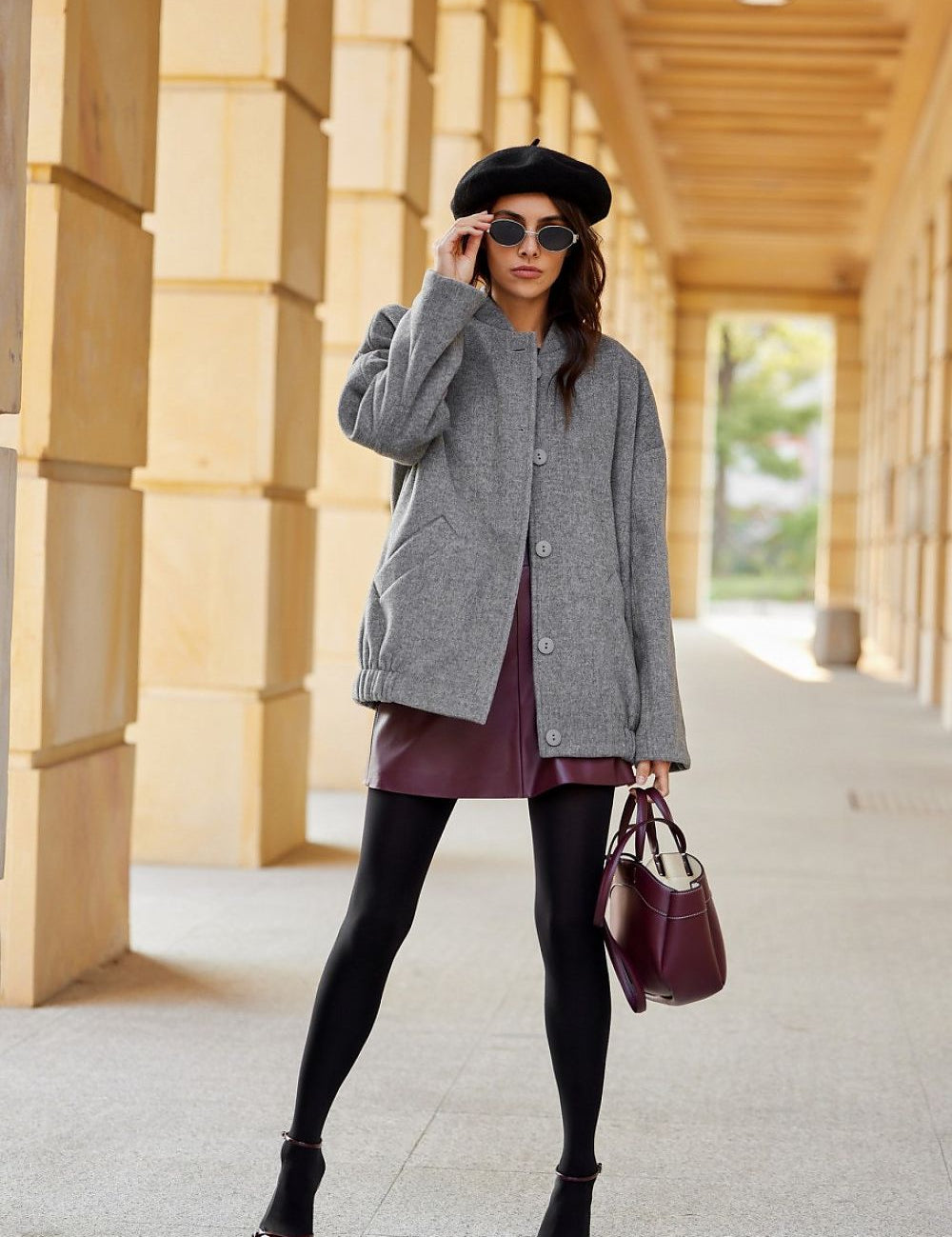 Woman wearing a Vernelle stand-collar buttoned jacket with dropped shoulders and a gathered hem, paired with a beret and sunglasses.
