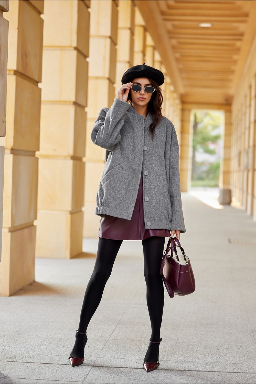 Woman wearing a Vernelle stand-collar buttoned jacket with dropped shoulders and a gathered hem, paired with a beret and sunglasses.