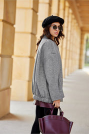 Woman wearing Vernelle Stand-Collar Buttoned Jacket, showcasing dropped shoulder design and gathered hem, with stylish hat and bag.