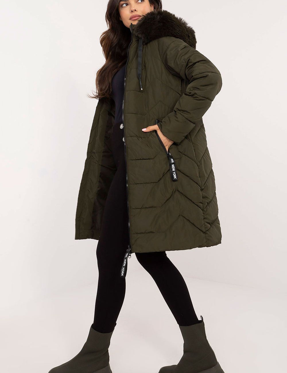 Woman modeling Elvarra Quilted Winter Down Coat with fur-trimmed hood, showcasing knee-length urban design in green, perfect for winter.