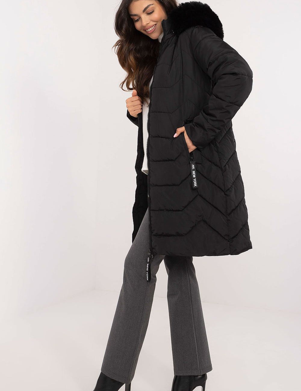 Woman wearing Elvarra Quilted Winter Down Coat, knee-length with detachable fur hood, showcasing stylish and warm urban autumn outfit.
