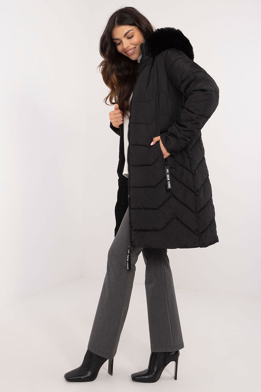 Woman wearing Elvarra Quilted Winter Down Coat, knee-length with detachable fur hood, showcasing stylish and warm urban autumn outfit.